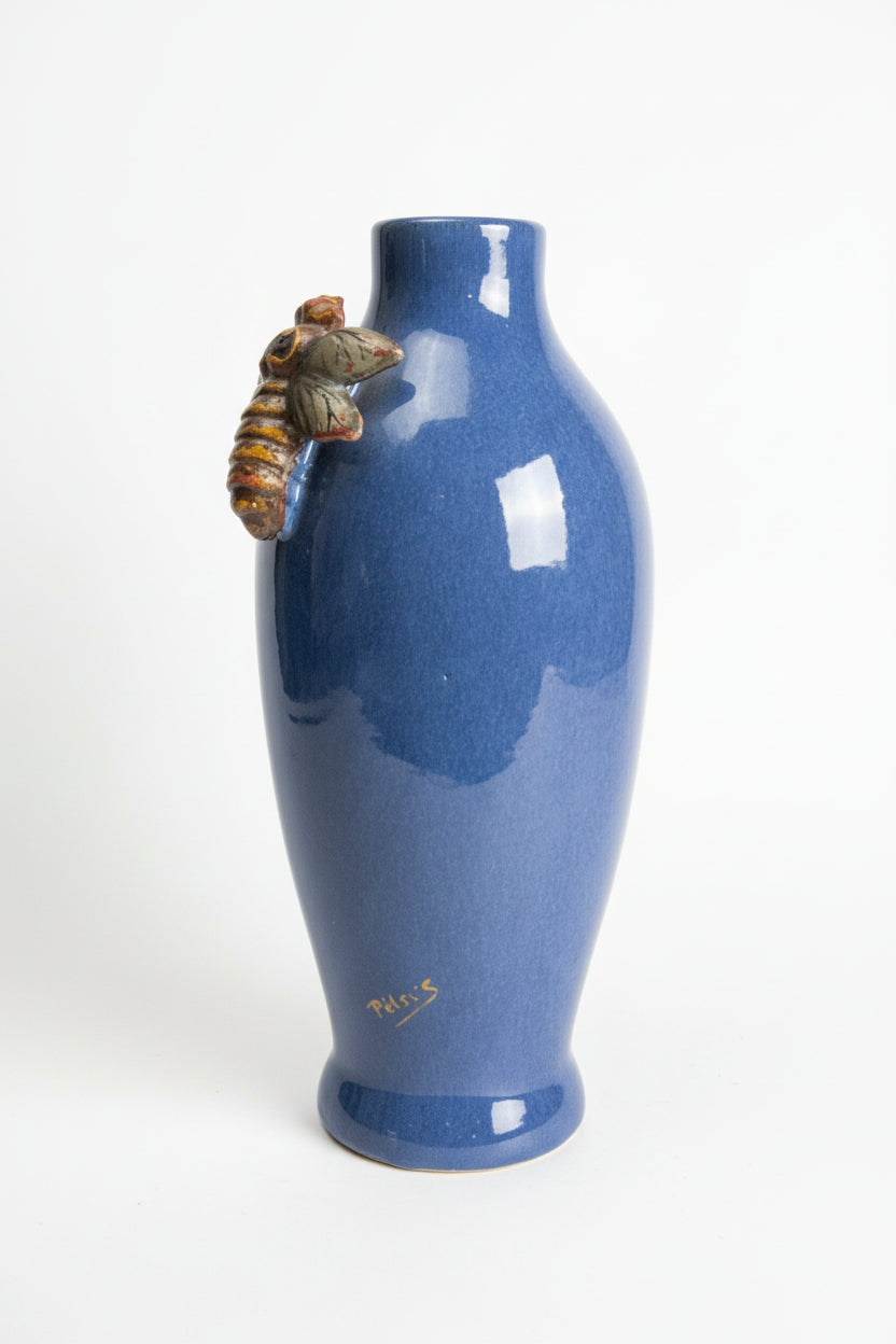 Blue ceramic bottle with a small figurine on a dark surface