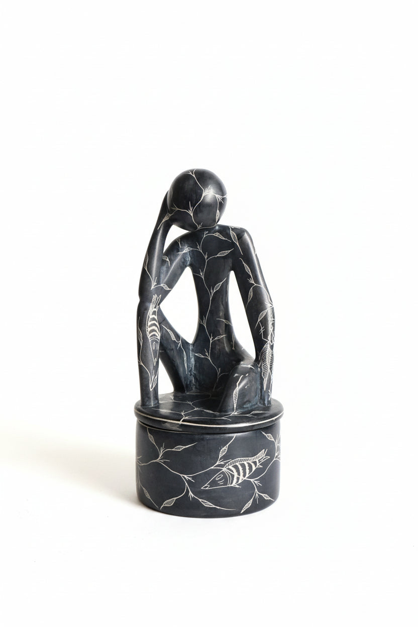 Decorative stone sculpture of a hand holding a fish on a dark background