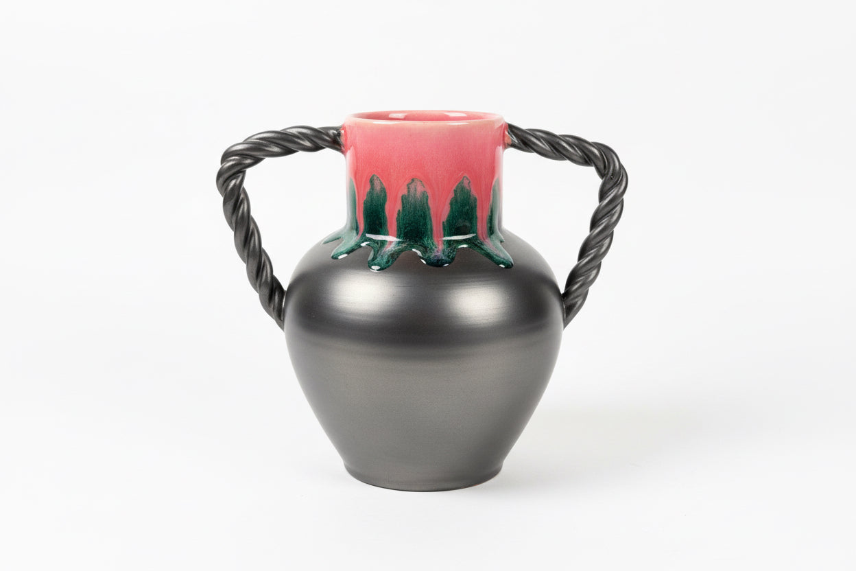 Black pot with pink base and rope handle on a dark surface