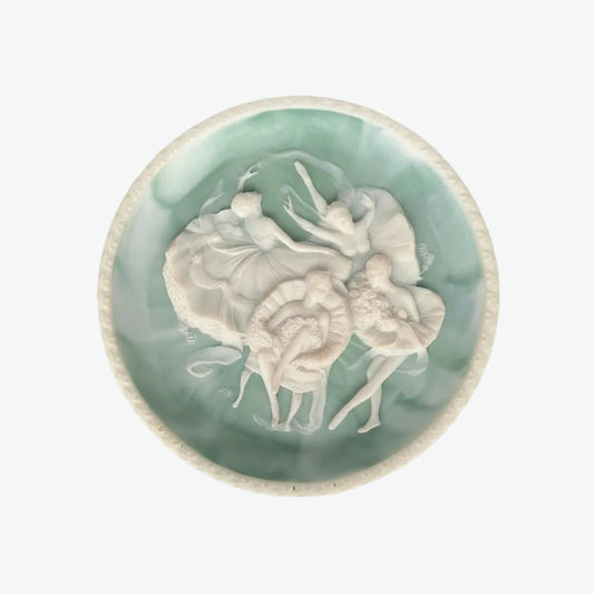 Decorative plate with a central relief of ballet figures on a light green background