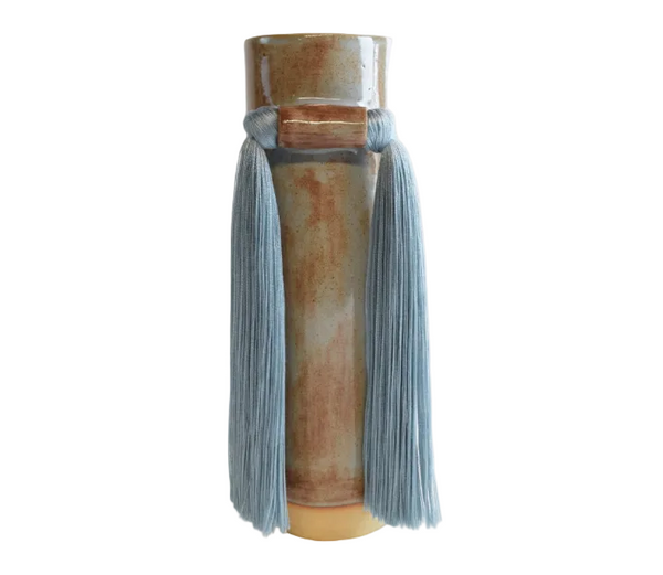 Cylindrical ceramic vase with ribbed texture and blue tassels on a white background