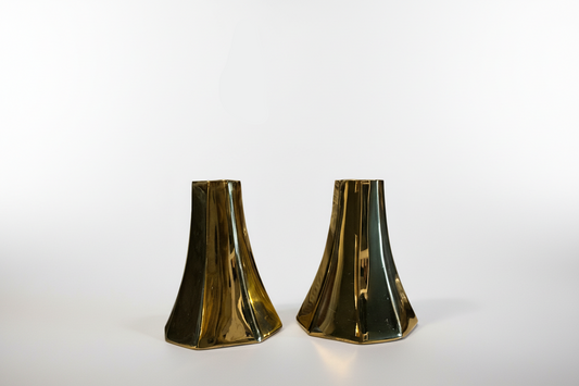 Two brass glass candle holders on a white background